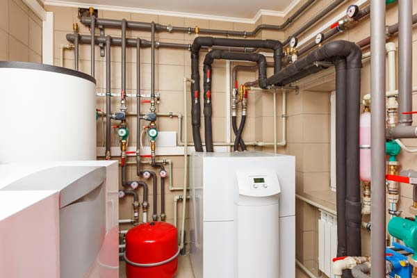 An indoor heating unit with many pipes and readers in a basement